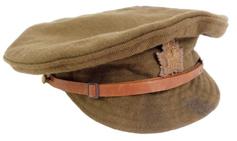 A WWI Canadian army peak cap, dated 1916, with leather adjusting belt and Canada cap badge, 22cm diameter.