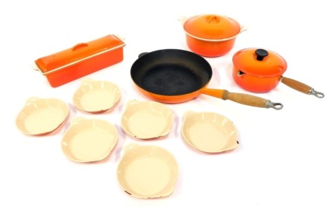 A group of Le Creuset cast iron wares in orange, to include milk pan and lid, 17cm diameter, frying pan, dish and cover, rectangular dish and cover, and six open dishes.