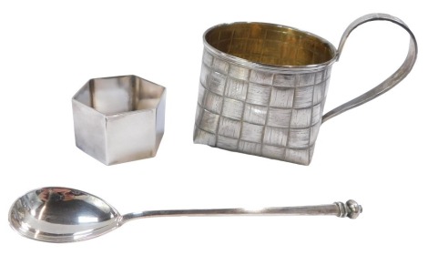 An Elizabeth II hexagonal silver napkin ring, of plain design, and a white metal crown handled spoon, unmarked, 2.10oz, and a silver plated basket mug. (3)