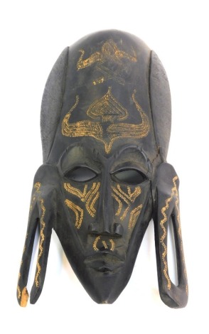 An African ebonised tribal mask, of a gentleman with elongated forehead and ear lobes, 39cm high. (AF)