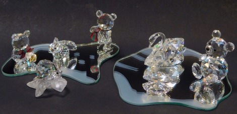 A group of Swarovski crystal animals, comprising snail, clam, swan, three Teddy bears, a hare, and two mirrored stands.