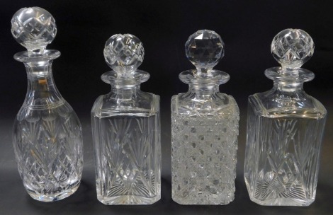 Four cut glass decanters and stoppers, three of square form, differing designs, 26cm high, and one of bottle form, 29cm high.