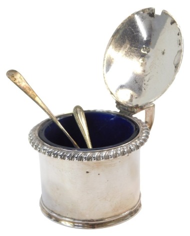 A silver mustard pot, with a fluted border and shell capped thumb piece, with blue glass liner, rubbed hallmarks, and two later silver spoons, one preserve spoon, one teaspoon, 5.14oz. (3)