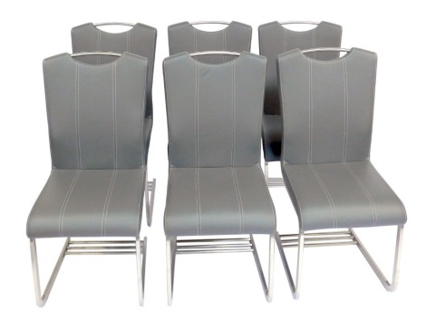 A set of six modern dining chairs, each with a grey leatherette seat and back, with cream stitching, on a chrome shaped base united by three stretchers. 
The upholstery in this lot does not comply with the 1988 (Fire & Fire Furnishing)...