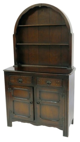 A 20thC oak dresser, the arched top with two plate shelves, the base with two drawers above two panelled cupboards, on reeded stiles, 158cm high, 92cm wide, 42cm deep.