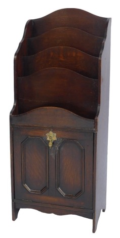 An early 20thC oak magazine rack, with a waterfall top with four recesses, the base with a panelled pullout door 97cm high, 39cm wide, 26cm deep.