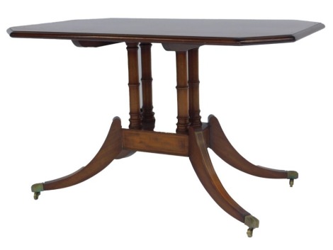 A 20thC mahogany occasional table, the rectangular top with canted corners and line inlay, on four cylindrical turned columns with square box under tier, on sabre legs with brass paw capped castors, 54cm high, the top 86cm x 54cm.