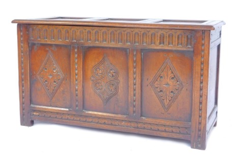 An oak coffer, the hinged three panelled top enclosing a vacant interior, the front with three carved panels, on stiles, 57cm high, 106cm wide, 44cm deep.