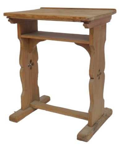 A pine lectern, the rectangular top, strut support with under tier, raised on two carved and pierced end supports united by a H-shaped stretcher, 74cm high when flat, 56cm wide, 46cm deep.