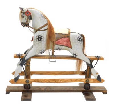 A dapple grey painted rocking horse, with part leather saddle, etc., on oak stand with turned supports, 152cm long.