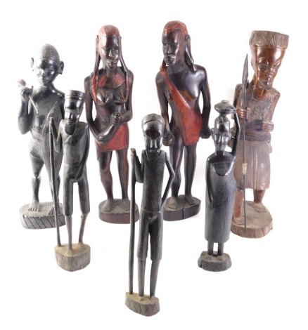 A pair of African tribal male and female figures, each embellished in red, 47cm high, and five other figures.