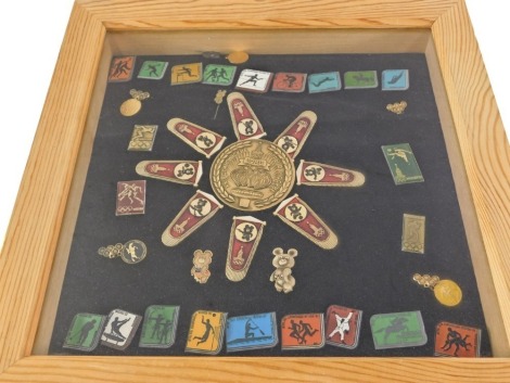 A quantity of Russian 1980 Olympics enamel finish badges, surrounding a central medallion, framed.