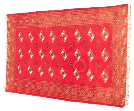 A Turkoman rug, with a design of lozenges on a red ground, 106cm x 198cm.