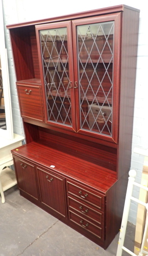 A mahogany wall unit, with cupboard and glazed top above arrangement of two cupboards and three drawers.