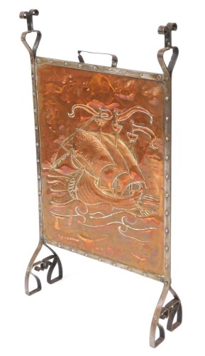 An late 19thC Arts & Crafts copper and cast iron framed firescreen, possibly Newlyn School, the central panel embossed with a medieval sailing ship, 101cm, high, 57.5cm wide.