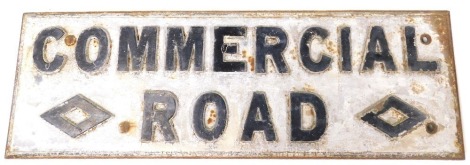 An early 20thC cast iron road sign "Commercial Road", with black raised lettering on a white ground, 92.5cm wide.