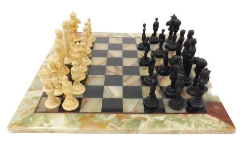 A green onyx and black slate chessboard, with Indian figural resin chess pieces.