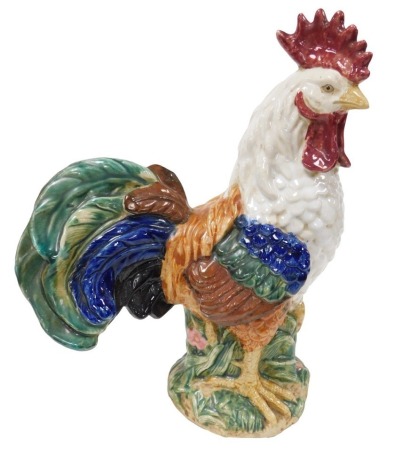 A 20thC Chinese pottery figure of a cockerel, modelled in standing pose, on a leaf and floral moulded base, 41cm high.