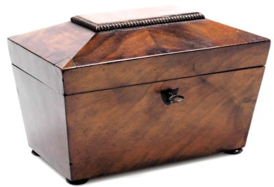 A Regency mahogany sarcophagus form tea caddy, the hinged lid opening to reveal two lidded compartments, raised on bun feet, with key, 22.5cm wide.