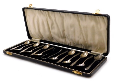 A set of eleven George V silver coffee spoons, cased, Birmingham 1930, 4.21oz, together with a pair of sugar nips, stamped sterling, 0.68oz, and an unmatched stainless steel spoon.