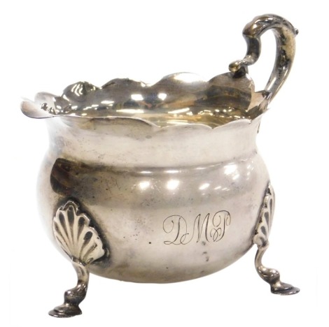 A Victorian silver cream jug, monogram engraved, raised on three shell capped hoof feet, William Aitken, Chester 1898, 3.18oz.