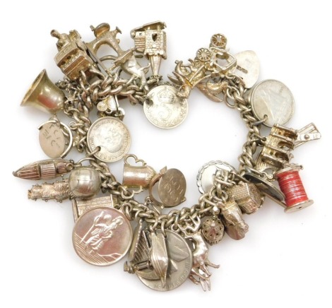 A silver curb link charm bracelet, with safety chain and hard shaped padlock clasp, together with thirty charms or coins as fitted, 3.59oz.