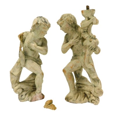 A pair of 17thC cream painted pine furniture appliques, modelled as putti, 22cm high.