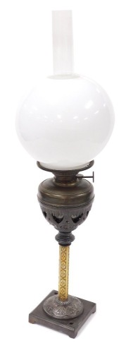 An early 20thC German cast iron and brass oil lamp, the wizard, with chimney and white glass globular shade, 66cm high.