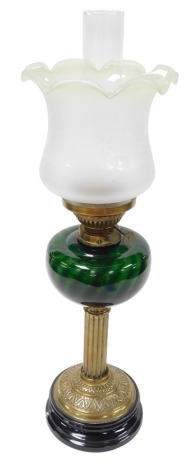 An early 20thC brass oil lamp, with a green glass reservoir, on a black socle, with chimney and Art Nouveau frosted to green glass shade, 65cm high.