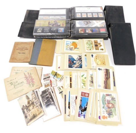 Philately and cartophily, comprising three cover albums of post decimalisation mint commemorative sets, an empty album, together with Wills and Players cigarette cards, Brooke Bond tea cards, postcards etc. (qty)