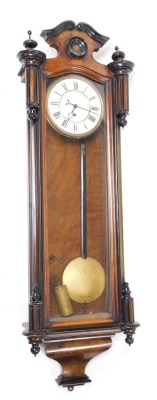 A late 19thC walnut and ebonised cased Vienna wall clock, circular brass dial with enamel chapter ring bearing Roman numerals, single train thirty hour movement, the case with a shaped pediment, and glazed front, with pendulum, weight and key, 110cm high.