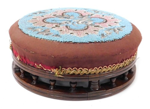 A Victorian mahogany and beadwork upholstered footstool, 30.5cm diameter.