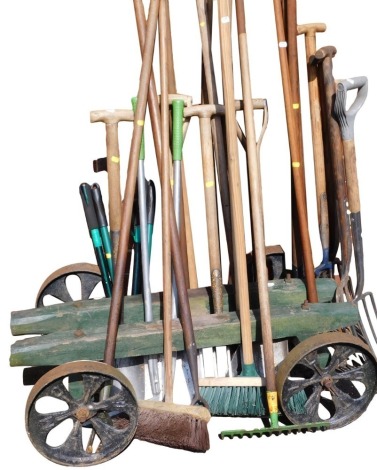 Assorted garden tools, including forks, spades, hoes, shears, and loppers, together with a wooden trolley with cast iron wheels, 102cm wide.