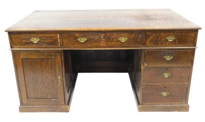 An early 20thC oak twin pedestal desk, with one long frieze drawer, flanked by a frieze drawer above a cupboard door to the left, four frieze drawers to the right, raised on plinth bases, 78cm high, 151cm wide, 86cm deep.