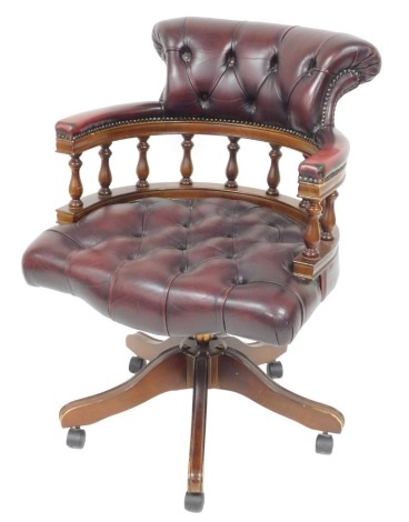 A mahogany and oxblood leather captain's chair, with button back headrest and overstuffed seat, raised on five cabriole legs, on castors, 62cm wide.