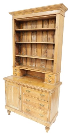 A Victorian Lincolnshire pine dresser, the outswept pediment above an open bookcase of four shelves, over two small drawers above a cupboard flanked by three further drawers, raised on a plinth above turned feet, 206cm high, 104cm wide, 46.5cm deep.