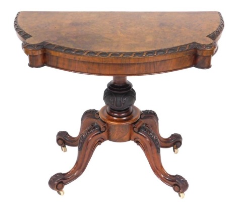 A Victorian walnut demi-lune foldover card table, raised on a turned and leaf carved column over four leaf carved cabriole legs, on castors, 72cm high, 90cm wide, 45cm deep.