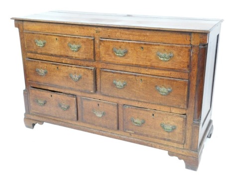 A George III oak and mahogany cross banded Lancashire mule chest, with four long over three short drawers, flanked by quarter pilasters, raised on bracket feet, 90cm high, 143cm wide, 53cm deep.