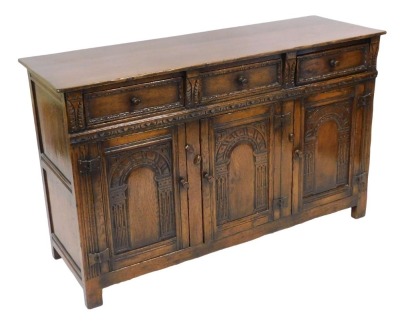 A Titchmarsh & Goodwin oak sideboard, with three drawers, over three carved panelled doors, raised on stiles, 84cm high, 137cm wide, 48cm deep.