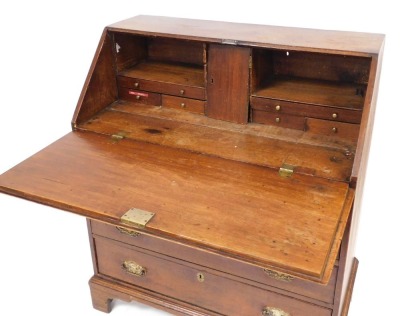 A George III oak bureau, the fall flap opening to reveal a central door flanked by two recesses and six drawers, over four long graduated drawers, raised on bracket feet, 120cm high, 94cm wide, 52cm deep. - 2