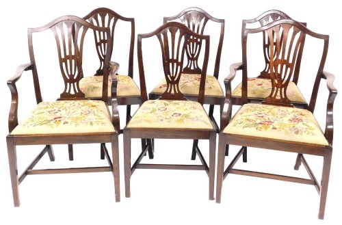 A set of six Hepplewhite style mahogany dining chairs with shield shaped backs, drop in floral tapestry seats, raised on tapering square legs united by a H frame stretcher, comprising a pair of carvers and four single chairs.