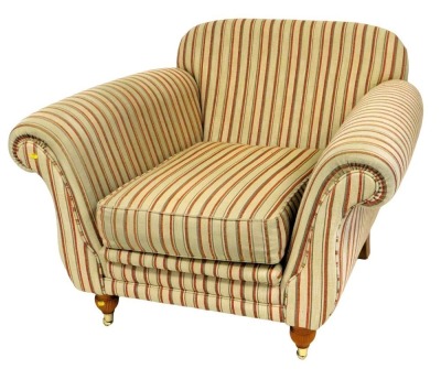 A large deep seated armchair, with gold and red striped fabric, on reeded turned legs with brass castors, 113cm wide.