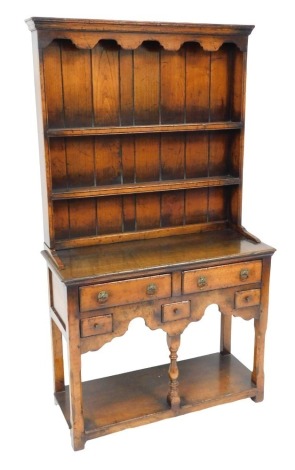 A Georgian style oak dresser, possibly Titchmarsh & Goodwin, the plate rack with an out swept pediment over a shaped apron, above two shelves, the base with two long and three short drawers, raised on turned supports united by an under tier, 163cm high, 9