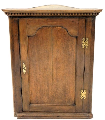 An early 19thC oak corner cabinet, singled panelled door, 92cm high, 73cm wide.