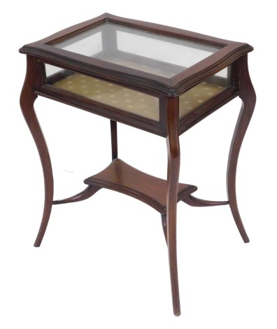 An Edwardian mahogany bijouterie table, with a glazed hinged lid and sides, raised on slender cabriole legs united by an under tier, 76cm high, 62cm wide, 46cm deep.