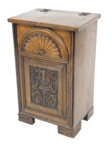 A Victorian oak side cupboard, the front carved with stylised fan, over a panel with foliate scrolls, raised on block feet, 68cm high, 43cm wide, 32.5cm deep.