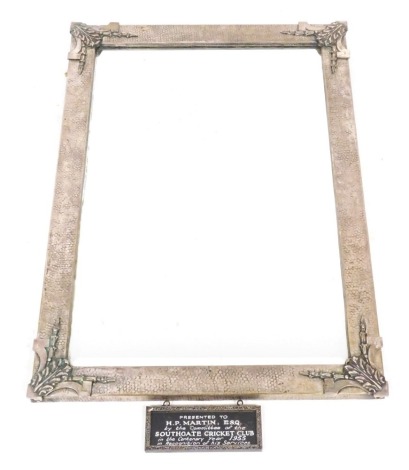 An early 20thC plate mounted wall mirror, cast with leaves and harebells, the frame with a textured finish, inset bevelled glass, with a sperate presentation plaque, 69cm x 49cm.