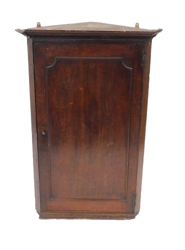 A George III oak wall hanging corner cupboard, the out swept pediment over a panelled door enclosing four serpentine shelves, raised on a plinth base, 122cm high, 81cm wide, 45cm deep.