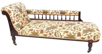 A Victorian mahogany chaise longue, upholstered in overstuffed floral and foliate fabric, raised on turned legs, brass capped on castors, 162cm wide.