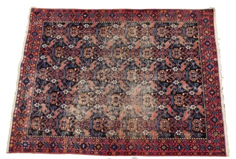 A Persian Sirjan black ground rug, decorated to the central field with flowers, within repeating floral borders, 220cm x 163cm.